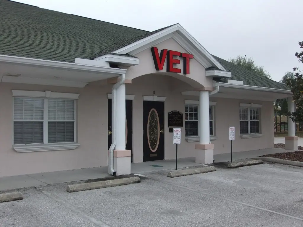 The Cross Creek Animal Medical Centre exterior in Tampa, FL features white columns, a red VET sign, and reserved parking spaces.