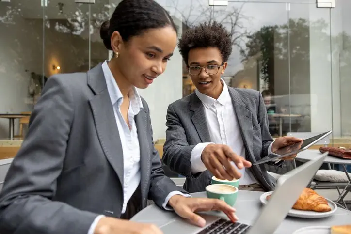 Business partners discussing something and working on laptop together