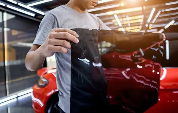 Technician holding dark window tint film during auto window tinting service in Kearny, New Jersey