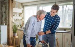 Family caregiver assisting older senior parent using a walker