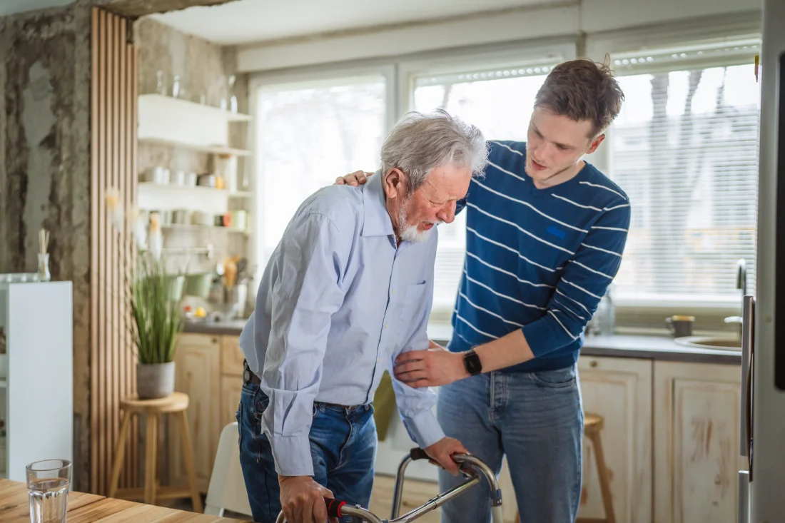 Family caregiver assisting older senior parent using a walker