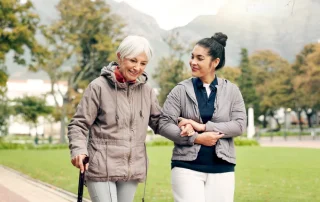 Senior woman walking with professional memory care caregiver in Tucson AZ