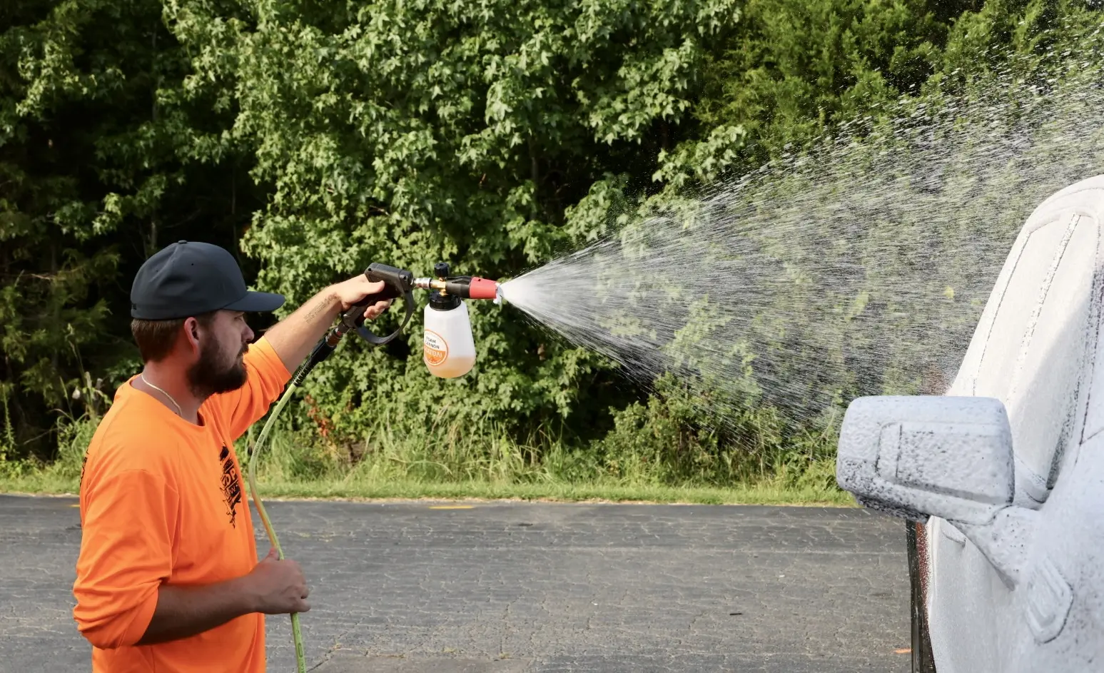 Technician washing a car hood during detailing preparation