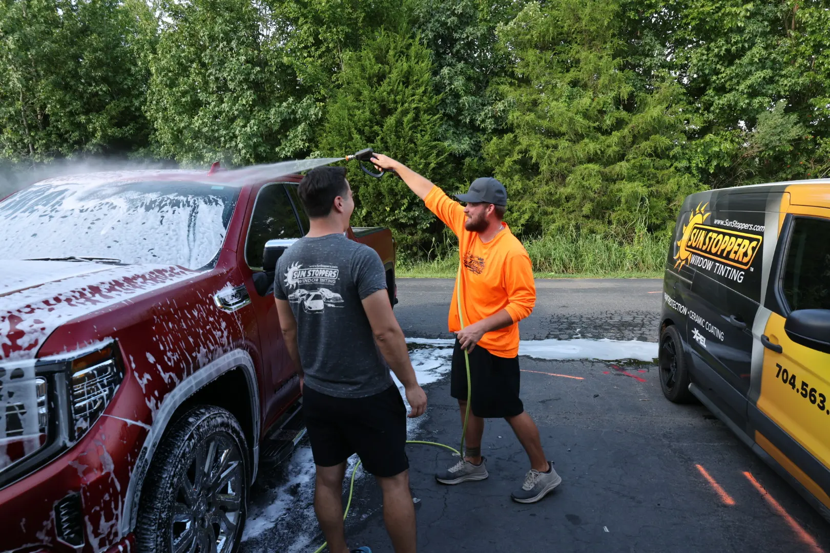 Sun Stoppers technician washing a car after automotive work