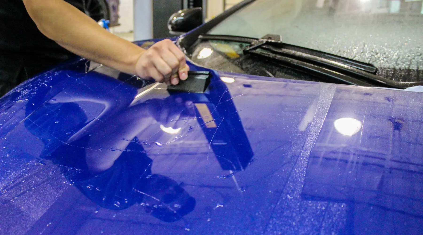 Professional XPEL paint protection film installation on a McLaren