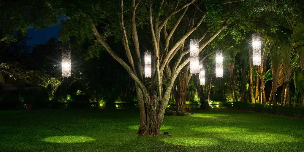 Hanging outdoor lights illuminate a lush green garden at night, creating a safe, well-lit yard area for pets.