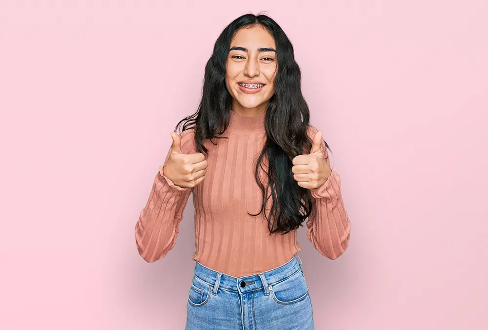 Teen girl with braces smiling, showing the importance of an expert cosmetic dentist in Oakdale