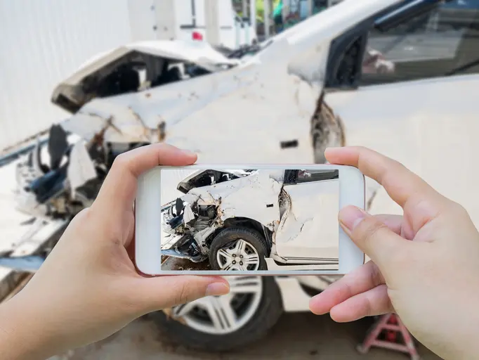 Female using mobile smart phone taking photo of the car crash accident damage for insurance