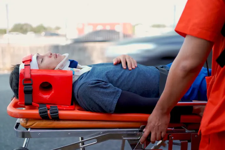 Emergency medical service team is rescuing Asian young man The emergency response team is trying to administer first aid to an Asian man who has had an accident on the side of the road.