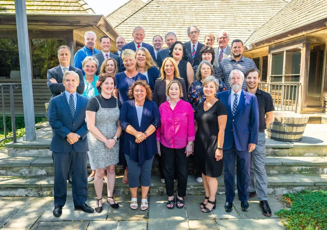 Our trusted team standing together outside on a sunny day on the beautiful office grounds.