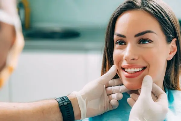 Image of woman smiling and a dentist holding her face