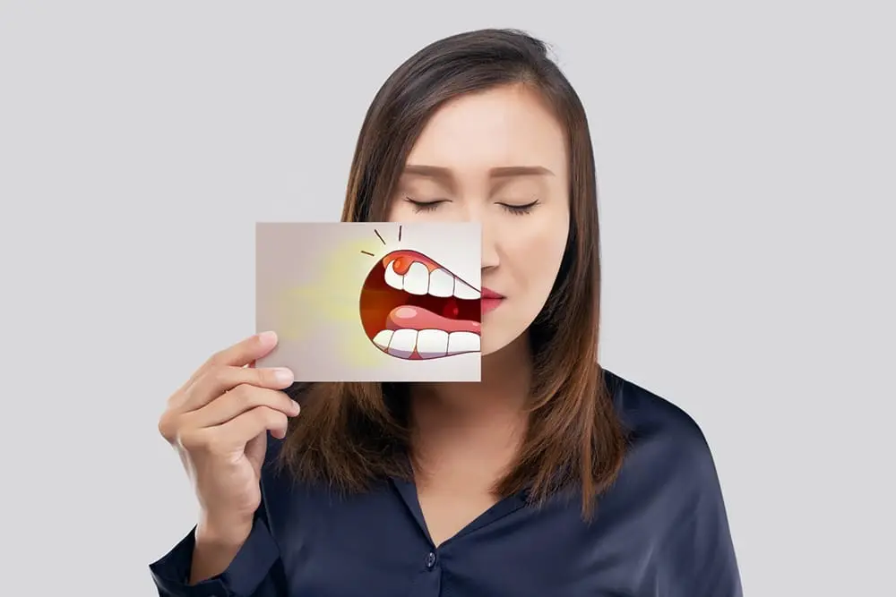Woman visibly experiencing dental pain, stressing the need for oral cancer screening in Midland