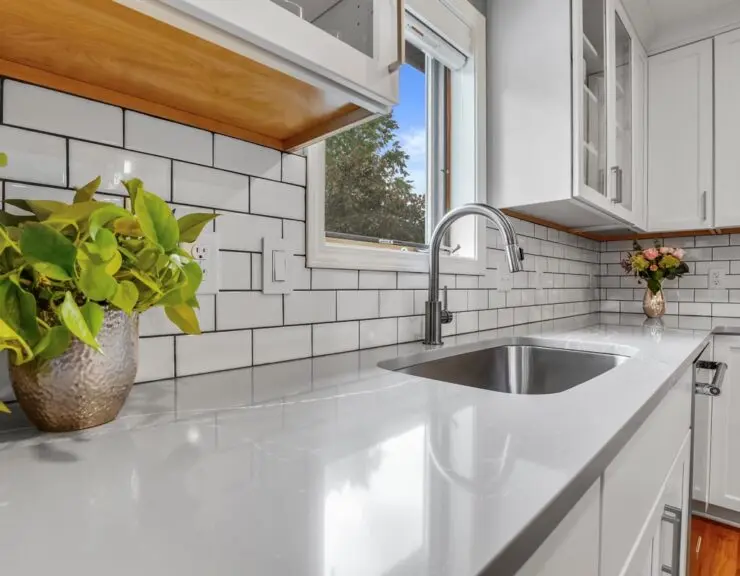 A modern kitchen featuring white cabinets and a stainless steel sink, creating a bright and clean atmosphere.