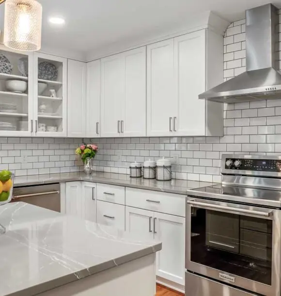 A modern kitchen featuring white subway tile walls and a stainless steel sink.