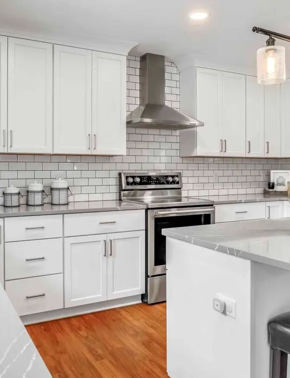 A modern kitchen featuring white cabinets and stainless steel appliances, showcasing a clean and organized space.