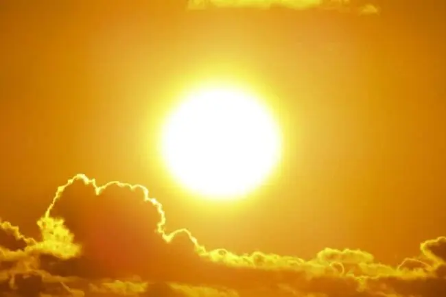 A bright sun is visible in the sky, surrounded by soft clouds, indicating favorable weather for roof services
