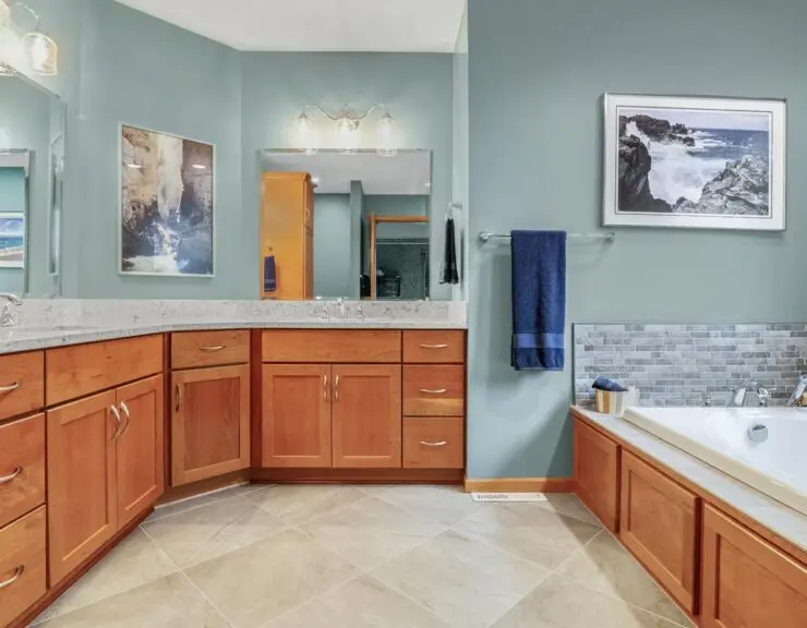 A spacious bathroom featuring a large tub and an expansive mirror reflecting the room's elegant design.