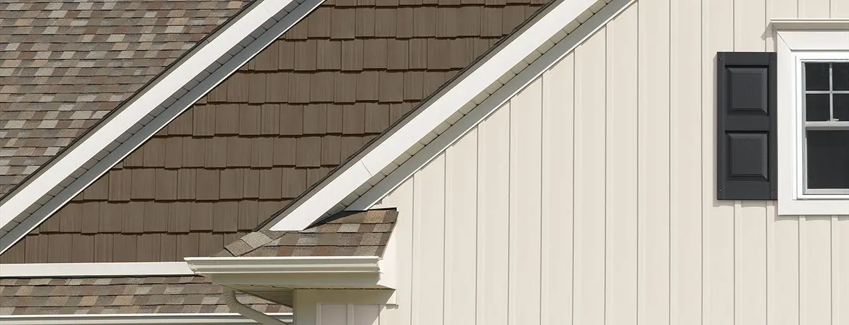 A house featuring a brown roof and black shutters, representing roofing services