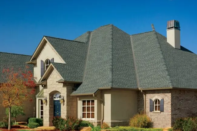 A large house featuring a gray roof, representing window replacement services.