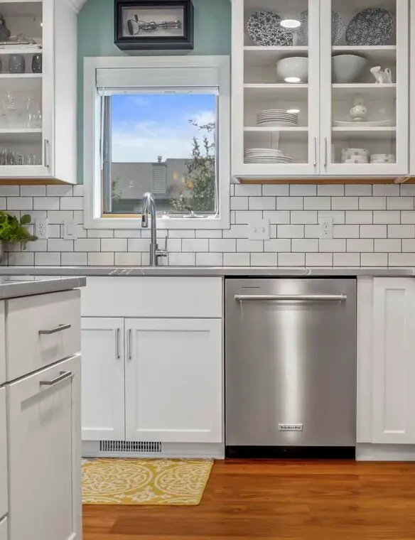 A modern kitchen featuring white cabinets and stainless steel appliances, showcasing a clean and organized space.