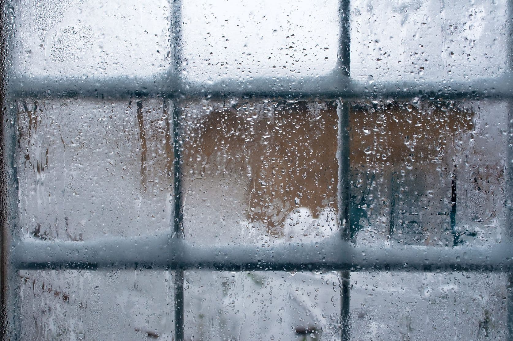 Close-up of a window adorned with frost, revealing a snowy landscape below, capturing the essence of winter.
