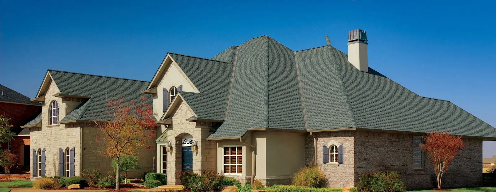 A large house featuring a gray roof, representing window replacement services.