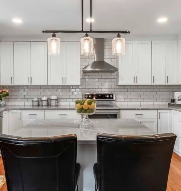 A modern kitchen featuring white cabinets and sleek black chairs arranged around a dining table.