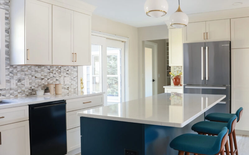 A kitchen featuring blue chairs and white cabinets, creating a bright and modern atmosphere.