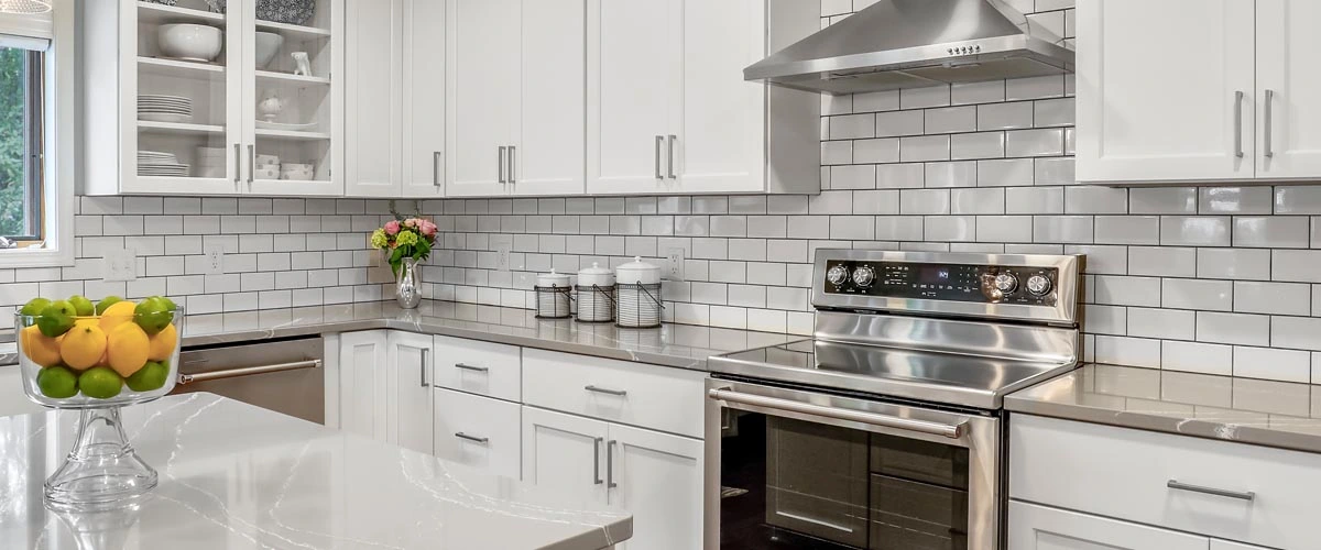 A modern kitchen featuring stainless steel appliances and sleek white cabinets.
