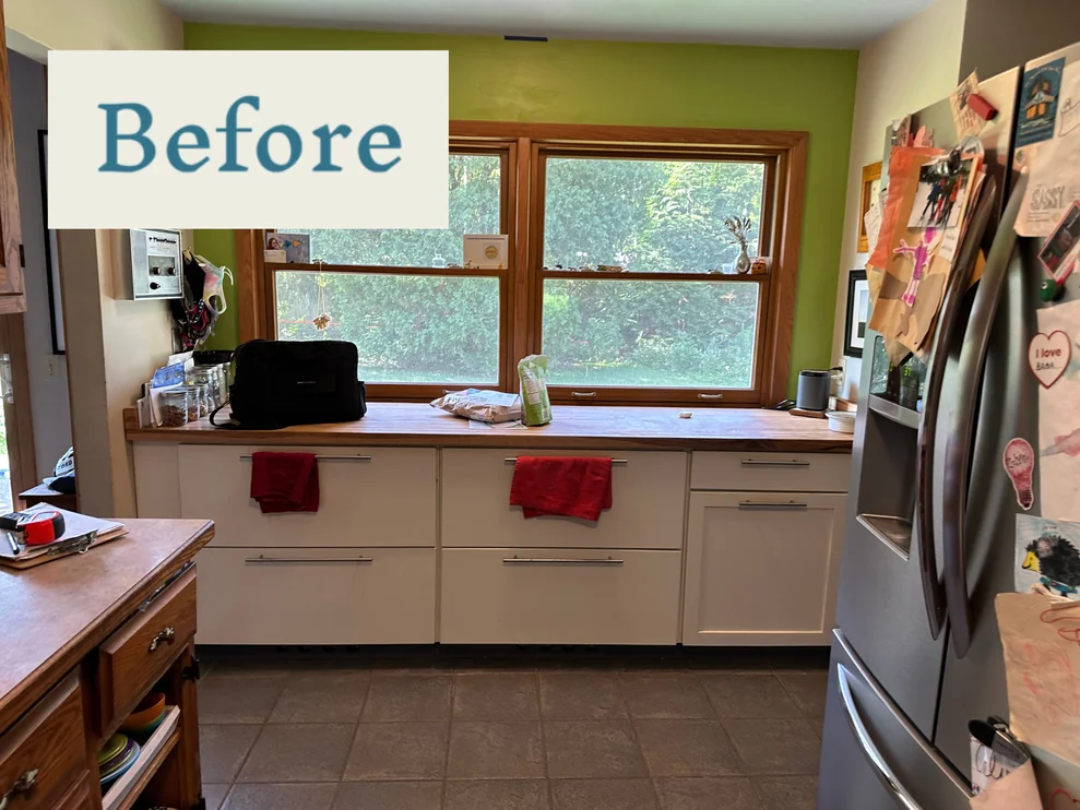 Before photo of outdated kitchen with white cabinets and wooden countertop.
