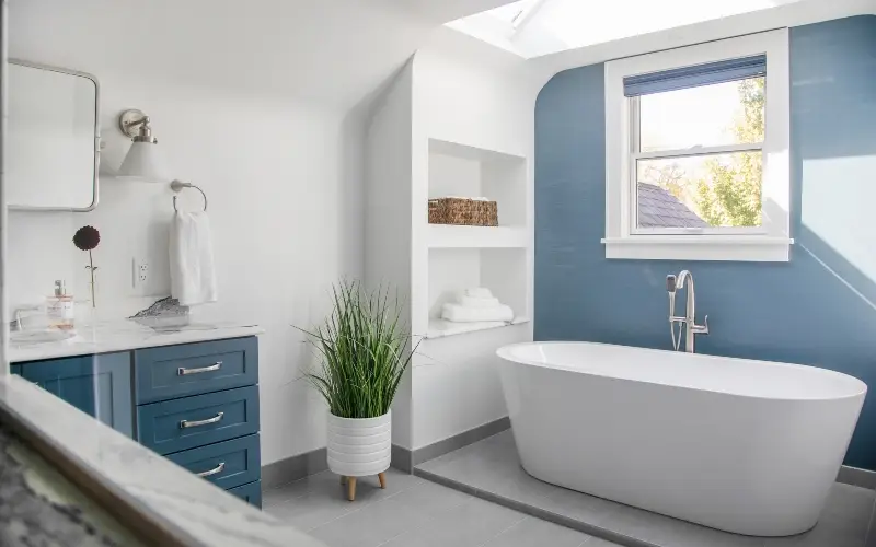 A blue bathroom featuring a white bathtub and sink, creating a clean and modern aesthetic