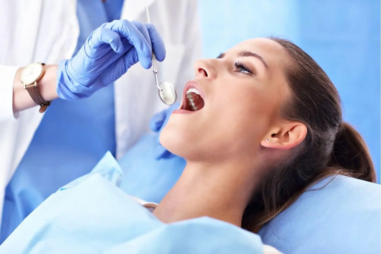 Patient reclining and dental mirror in mouth.