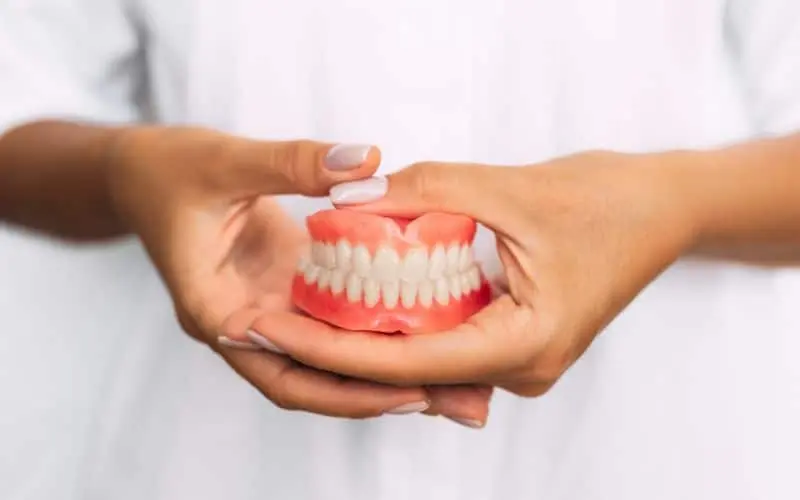 a dentist holding a complete dentures on their hands