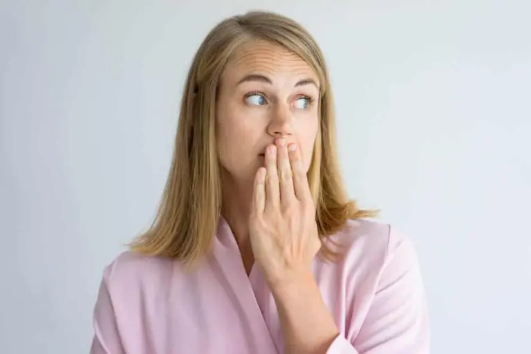I Take Care of My Oral Health: Why Does My Breath Stink 7 Concerned woman with hand covering mouth in discomfort.