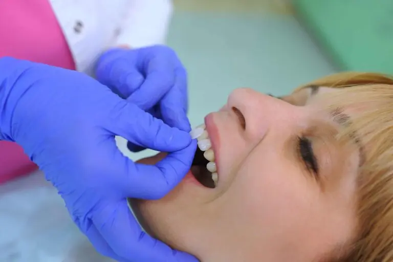 Dental hygienist applying fluoride or sealant to patient’s teeth.