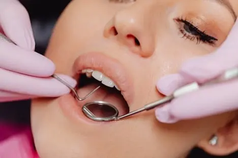 Failed Root Canal Symptoms: How to Recognize 5 Dental mirror examining teeth inside a patient’s mouth.