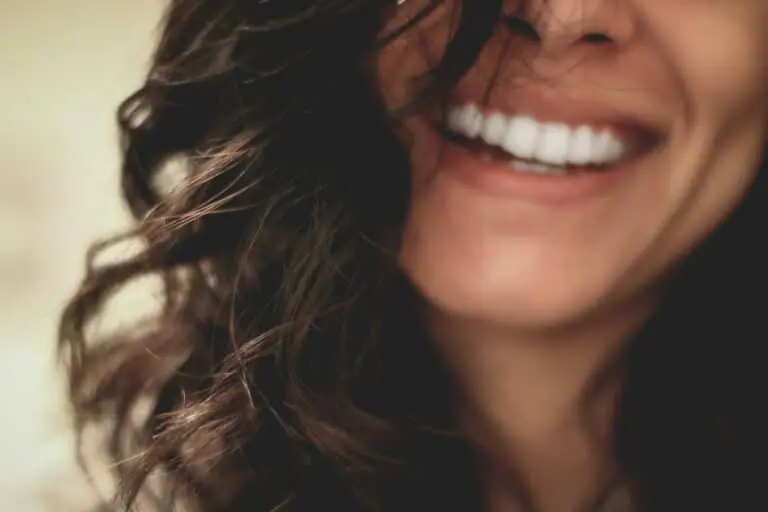 Smiling woman with long hair, partially covering her face.