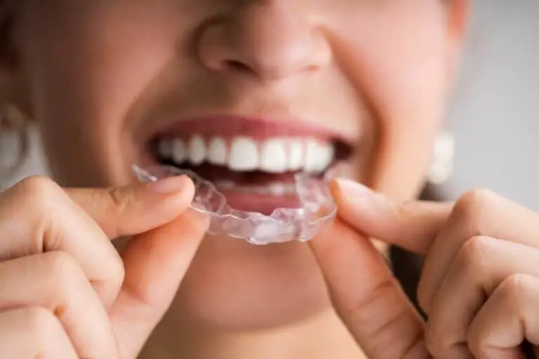 Smiling woman inserting clear aligner tray.
