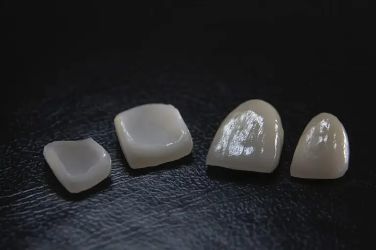 Porcelain veneers lined up on dark surface.
