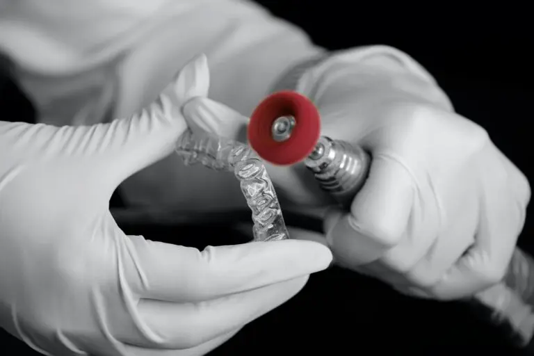Invisalign Refinements 1 Hands adjusting clear aligner over dental mold with red marker.