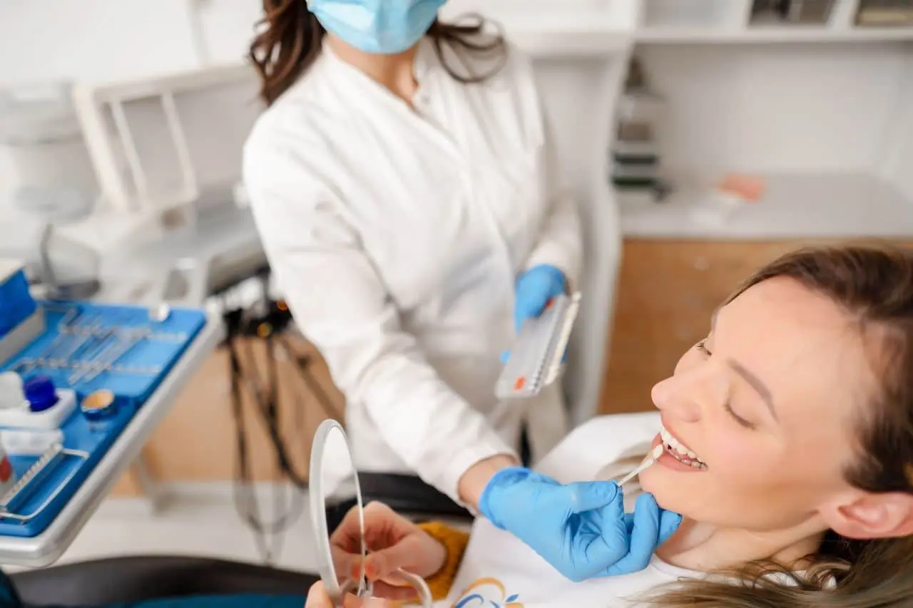 Dental assistant preparing tray while patient relaxes in chair.