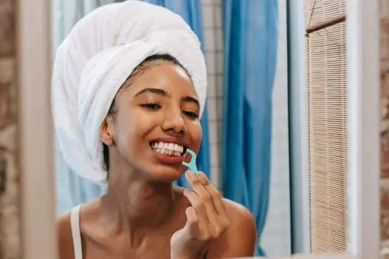 What is Plaque? Symptoms, Causes & Treatments 5 Woman brushing her teeth in the morning wearing towel wrap.
