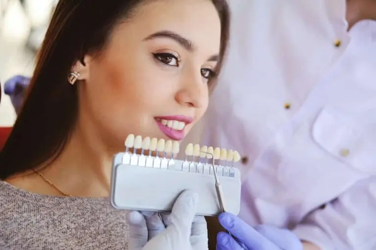Dental patient holding up tooth shade guide.