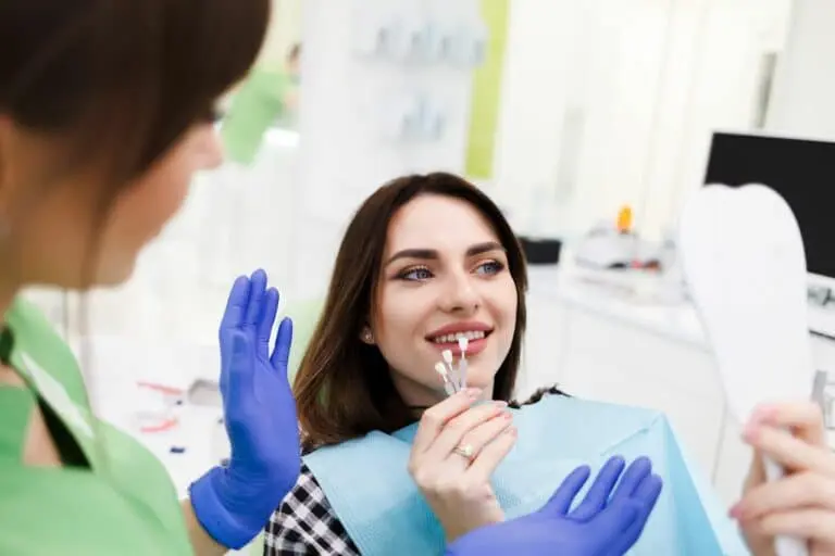 Dental professional handing Invisalign tray to smiling patient.