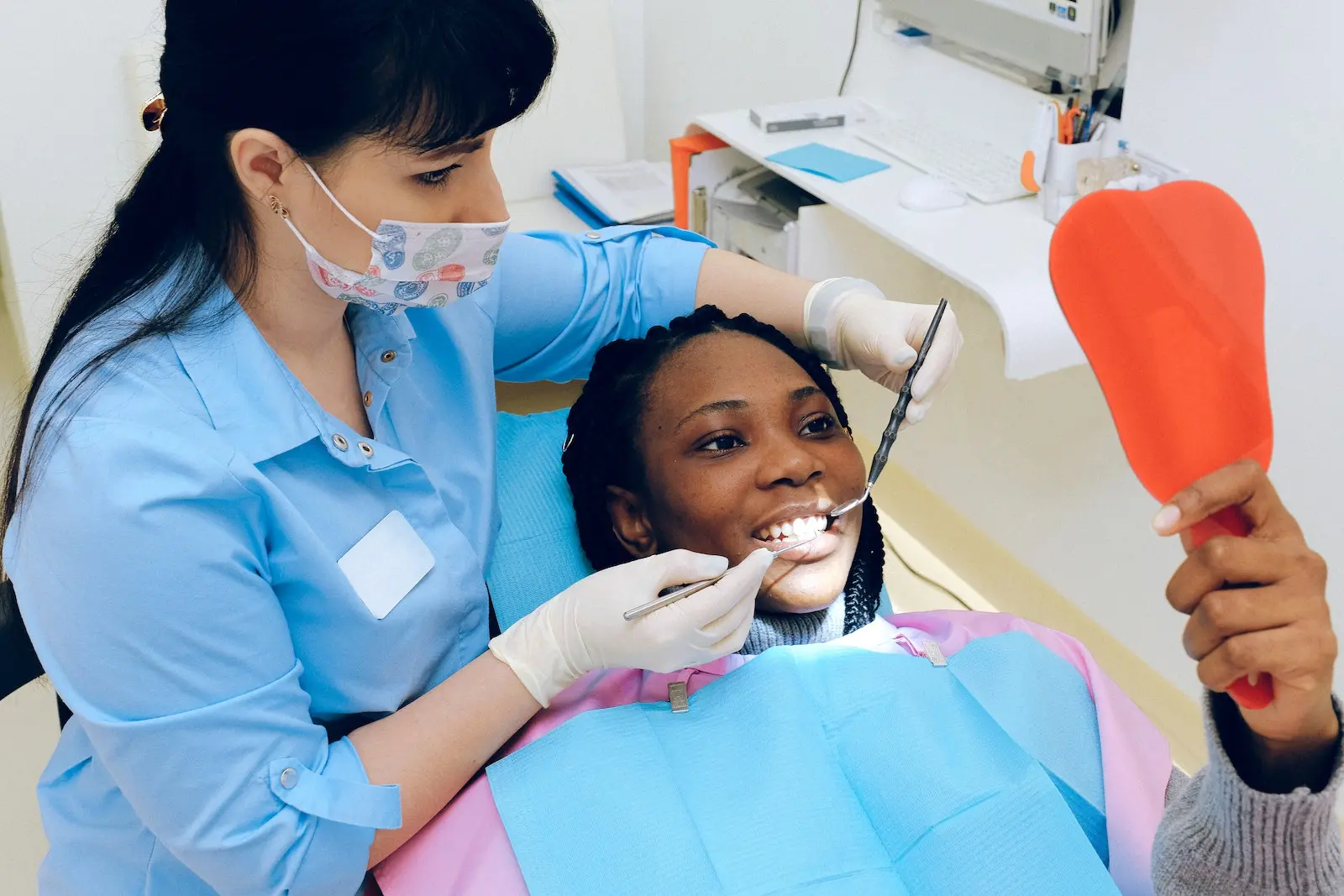 Before & After Root Canal 1 Dentist holding mirror for patient during dental consultation.