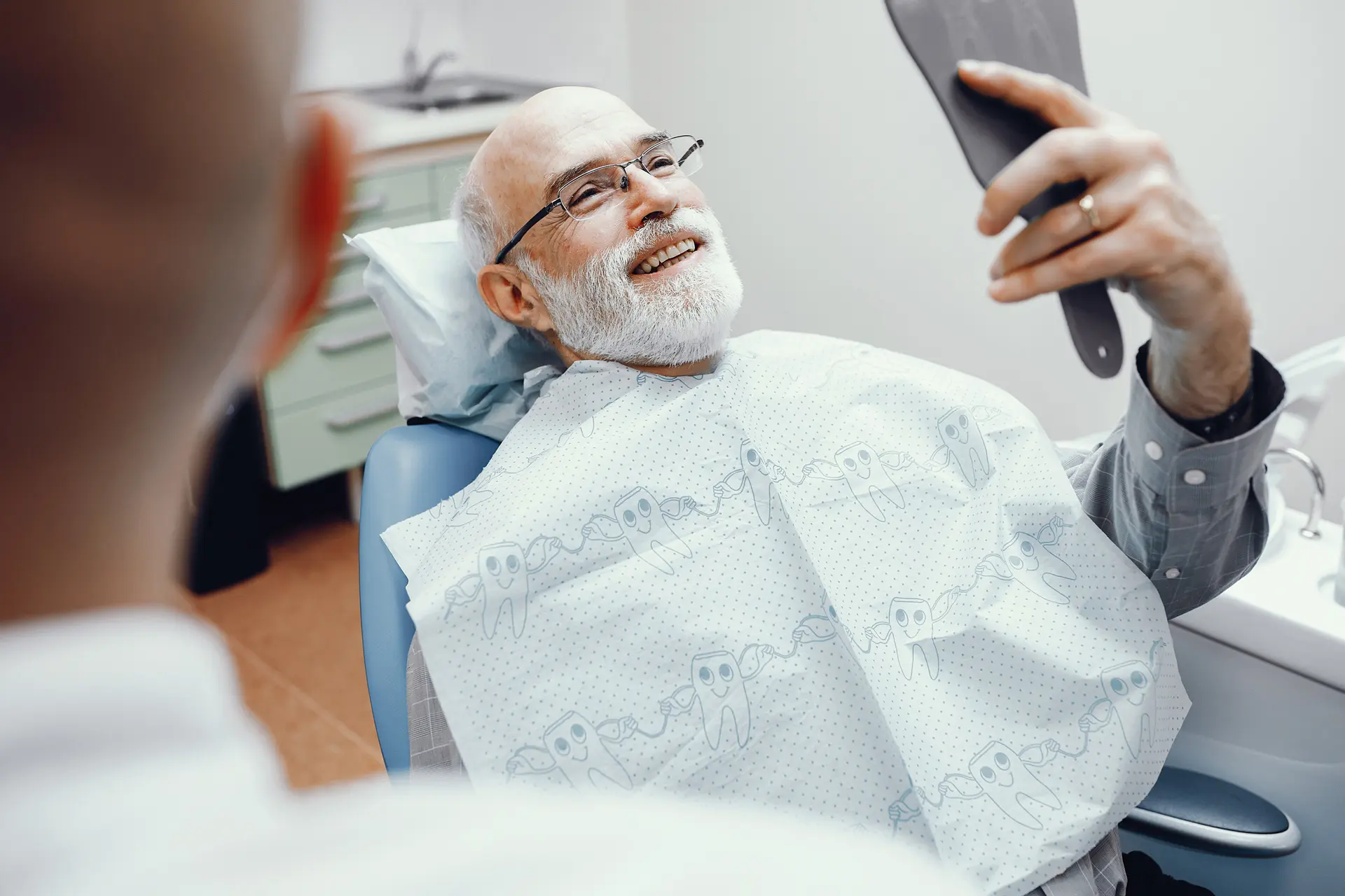 Reconstructive Dentistry 1 A man in a dental chair holding a toothbrush, preparing for a reconstructive dentistry procedure.