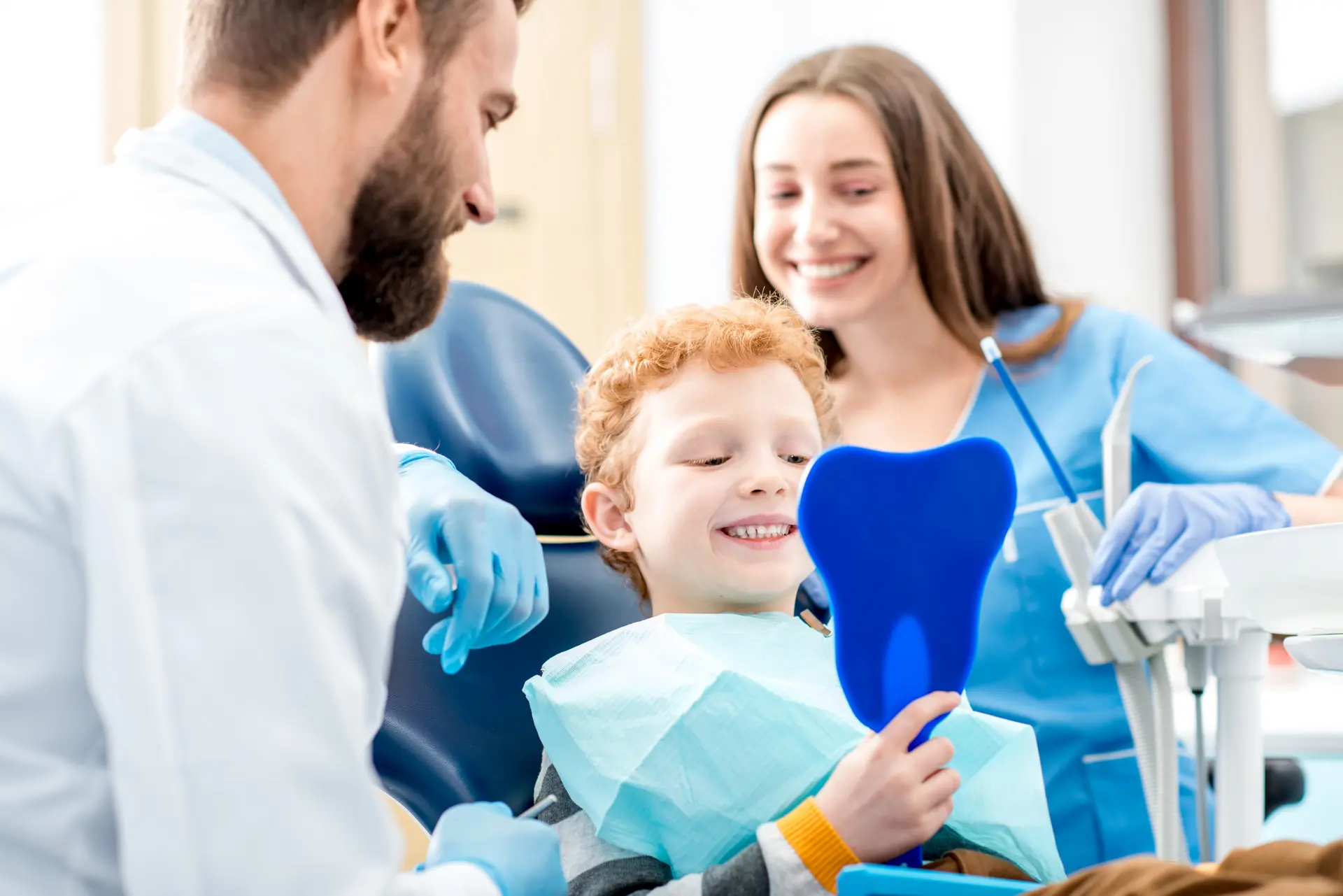 Pediatrics 1 A smiling child holds a mirror while sitting in a dental chair.