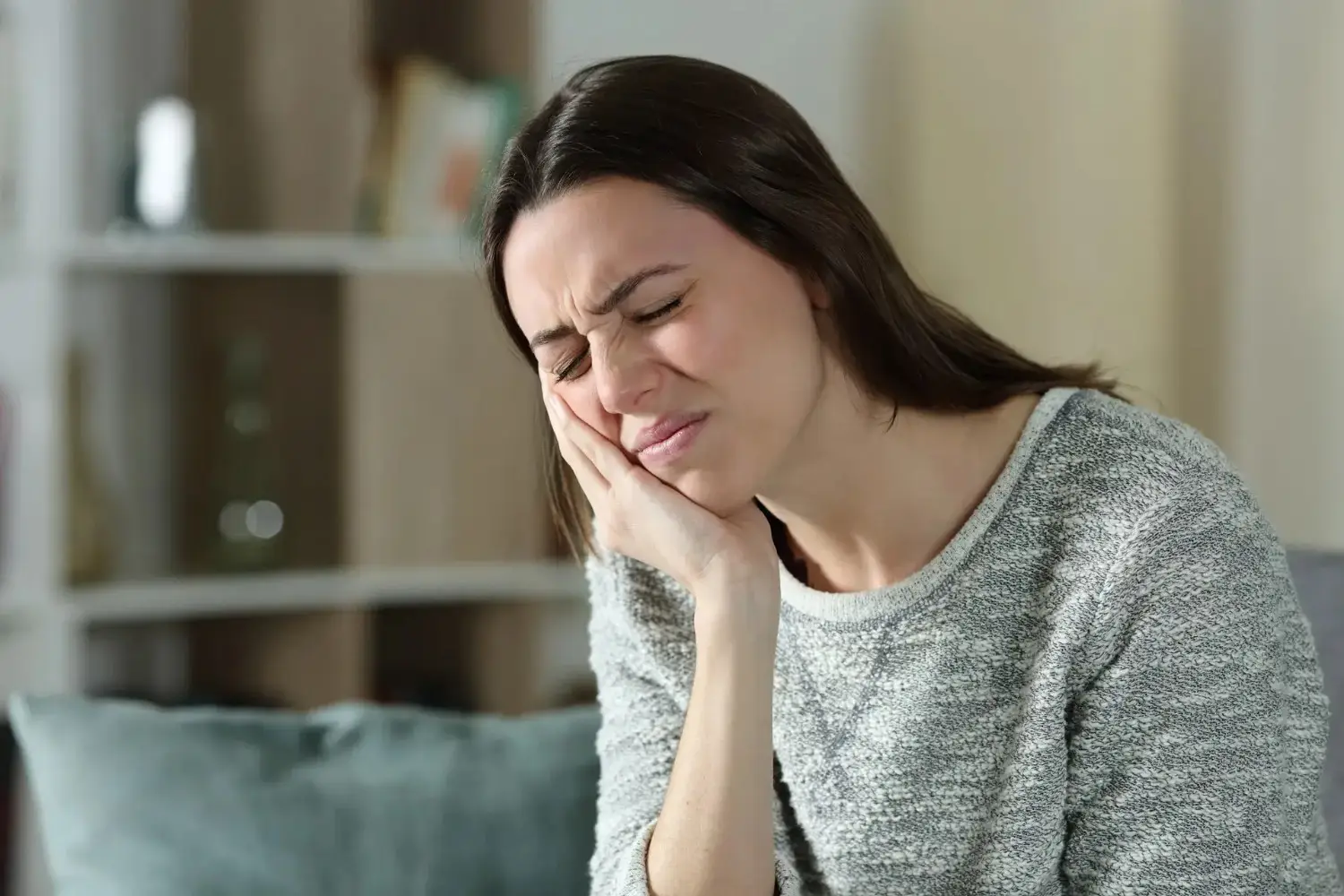 Woman in pain clutching cheek from dental issue – Tooth Extractions in Westbury, NY – Smallberg & Satornino, DDS, PLLC