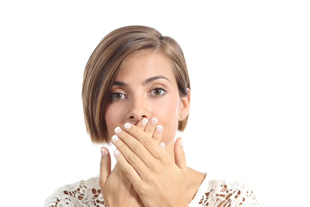 Dry Mouth | VP Dental | Dry Mouth Treatment in Raleigh A woman covering her mouth with both hands, looking concerned
