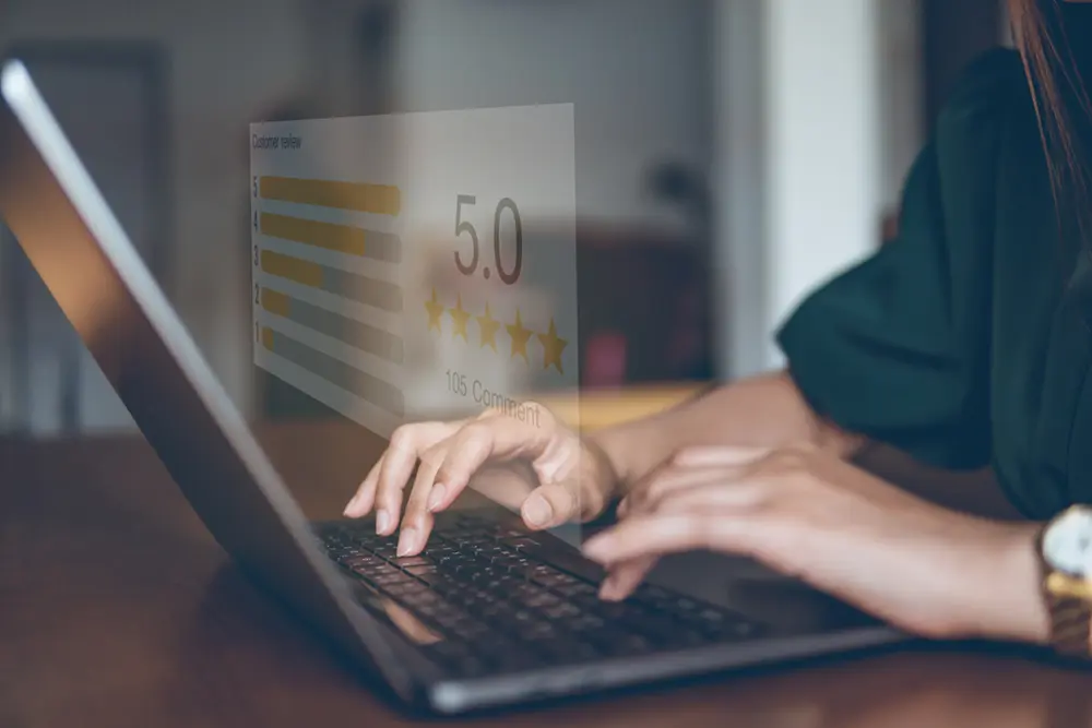 Reviews | VP Dental | Dental Reviews in Raleigh Person typing on a laptop with a holographic display showing a 5-star customer review and a 5.0 rating